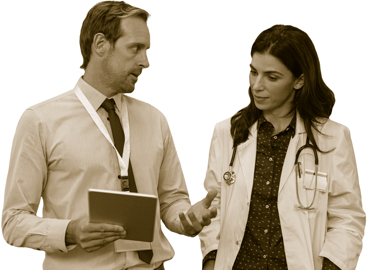 Man in button-up shirt and tie shows something on a clipboard or tablet to a woman doctor wearing a doctor coat and stethoscope